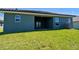 Home's backyard featuring well-maintained lawn, covered patio, and neutral-colored exterior at 5126 Villa Crest Way, Auburndale, FL 33823