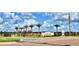 Community entrance featuring lush landscaping, brick accents, and elegant signage against a blue sky at 5126 Villa Crest Way, Auburndale, FL 33823