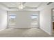 Neutral carpeted main bedroom with two windows, tray ceiling, and ceiling fan at 1365 Melrose St, Lake Alfred, FL 33850
