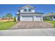 Two-story home featuring a three-car garage and landscaped front yard with a decorative driveway and palm tree at 4712 Grandview Glen Dr, Auburndale, FL 33823