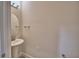 A neutral powder room with a pedestal sink, oval mirror, and minimalist decor at 4712 Grandview Glen Dr, Auburndale, FL 33823