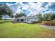 Well-maintained backyard showcasing the deck, white house, fenced garden, and lush green lawn at 6155 Bethlehem Rd, Mulberry, FL 33860