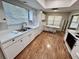 Bright kitchen featuring white cabinets, laminate floors, stainless sink, and plenty of natural light at 6718 Trail Ridge Dr, Lakeland, FL 33813