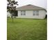 An exterior view of the house and backyard featuring a green lawn, windows, and back porch at 3136 Country Club Cir, Winter Haven, FL 33881