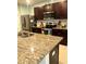 Close-up view of a kitchen featuring granite countertops, stainless steel appliances, and dark wood cabinets at 3136 Country Club Cir, Winter Haven, FL 33881