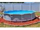 An above-ground swimming pool with a ladder and filter system surrounded by red mulch at 3136 Country Club Cir, Winter Haven, FL 33881