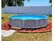 Backyard with an above-ground pool surrounded by red mulch and greenery, bordered by a white privacy fence at 3136 Country Club Cir, Winter Haven, FL 33881