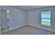 Bright bedroom with neutral walls, neutral carpet, and a window overlooking a landscaped yard at 4639 Grandview Glen Dr, Auburndale, FL 33823