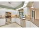 Modern white kitchen with stainless steel appliances, quartz countertops, and window views of the pool at 3845 Garnet Dr, Mulberry, FL 33860