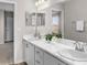Bathroom with double sinks, marble countertops, white cabinets, and a framed mirror at 5105 Sylas Jax Ave, Winter Haven, FL 33884