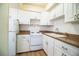 The kitchen features white cabinetry and white appliances, as well as wood-look floors at 561 Cameo Dr, Lakeland, FL 33803