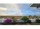 Expansive backyard with a white picket fence and colorful flowers under a vibrant rainbow at 1155 Towergate Cir, Lake Wales, FL 33853