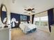 Inviting bedroom featuring a blue accent wall, ceiling fan, and a picturesque window view at 1155 Towergate Cir, Lake Wales, FL 33853