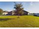 Charming home featuring a well-manicured lawn and a tree, set against a backdrop of clear blue skies at 1155 Towergate Cir, Lake Wales, FL 33853