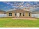 Wide backyard view showcasing green grass, patio area, and neutral colored house at 3226 Oak Tree Ln, Winter Haven, FL 33884
