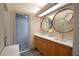Bright bathroom with double sinks, wood cabinets, tiled floor, and a glass-enclosed shower at 3226 Oak Tree Ln, Winter Haven, FL 33884