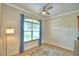 Bright living room featuring a ceiling fan, tan walls and a large window with blue curtains at 3226 Oak Tree Ln, Winter Haven, FL 33884