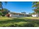 Spacious backyard with a well-maintained lawn and a view of the home's exterior, including a screened-in porch at 6029 Avocado Dr, Indian Lake Estates, FL 33855