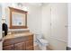 Well-lit bathroom with a wood vanity, granite countertop, and a white toilet at 6029 Avocado Dr, Indian Lake Estates, FL 33855
