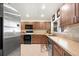 This kitchen offers brown cabinetry, neutral countertops, stainless steel appliances and tiled floors at 6029 Avocado Dr, Indian Lake Estates, FL 33855