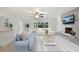 Bright living room boasts a ceiling fan, comfortable seating, and fireplace with scenic television above mantel at 6029 Avocado Dr, Indian Lake Estates, FL 33855