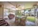 Relaxing screened-in porch with a ceiling fan, dining table, grill, and view of the backyard and canal at 6029 Avocado Dr, Indian Lake Estates, FL 33855