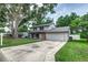 Two-story home featuring a two-car garage, orange front door, and mature trees at 1305 Avenue S Nw, Winter Haven, FL 33881