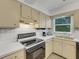 Kitchen with electric range, white countertops, and beige cabinets at 1704 Pineberry Ct, Lakeland, FL 33803