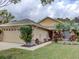 Tan house with a two-car garage, landscaping, and a welcoming entrance at 731 Lake Clark Ct, Lakeland, FL 33813