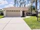 Beige house with two-car garage, landscaped lawn, and palm trees at 8052 Sugar Pine Blvd, Lakeland, FL 33810