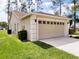 Tan house with two-car garage, landscaping, and large trees at 8052 Sugar Pine Blvd, Lakeland, FL 33810