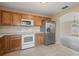 Kitchen showcasing stainless steel refrigerator, white appliances, and light wood cabinets at 3441 Grenville Dr, Winter Haven, FL 33884