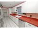 Traditional kitchen with red countertops, white cabinetry, stainless steel appliances, and tile flooring at 7101 Scenic Pl, Lakeland, FL 33810