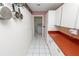 Galley kitchen featuring white cabinets, red countertops, tile flooring, and stainless steel appliances at 7101 Scenic Pl, Lakeland, FL 33810