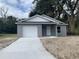 Newly constructed one-story home with gray exterior, white garage door, and a concrete driveway at 1108 Crestview Ave, Lakeland, FL 33805