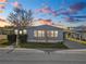 Mobile home exterior at sunset, featuring a carport and well-maintained landscaping at 2206 Golden Horseshoe N Cir, Lakeland, FL 33810