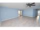 Spacious living room with light blue walls, ceiling fan, and wood-look flooring, and sliding glass doors at 2206 Golden Horseshoe N Cir, Lakeland, FL 33810
