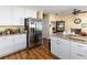 An additional view of the kitchen featuring granite countertops, white cabinetry, stainless steel appliances, and wood flooring at 1452 Grand Cayman Cir, Winter Haven, FL 33884