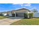 Exterior view of home's garage with updated door, neat landscaping, and green lawn at 1570 Doves View Cir, Auburndale, FL 33823