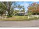 Single-story home with a large front yard, mature trees, and white fence at 1628 Lakewood S Dr, Lakeland, FL 33813