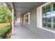 Covered porch with grey siding, white shutters, and tropical landscaping at 1628 Lakewood S Dr, Lakeland, FL 33813