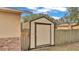 Tan colored storage shed with a wooden fence at 27 Moss E Rd, Auburndale, FL 33823