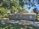 Backyard view of a single-story home with neutral siding surrounded by lush greenery and mature trees at 3016 Hutchins St, Eaton Park, FL 33840