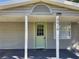 Welcoming front porch with a green door, white columns, and visible house number at 3016 Hutchins St, Eaton Park, FL 33840