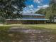 Two-story house exterior with metal roof, large yard and mature trees at 4850 Old Berkley Rd, Auburndale, FL 33823