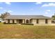 Tan single story home with gray roof, arched windows, and manicured lawn at 7738 Merrily Way, Lakeland, FL 33809