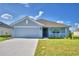 Single-story house with light blue exterior, two-car garage, and landscaped yard at 1214 Tagliamento Ln, Haines City, FL 33844