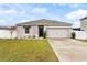 One-story house with a two-car garage and landscaped yard at 1405 Kissimmee Dr, Kissimmee, FL 34759