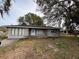 Gray house with a white door, stone accents, and mature trees at 1408 28Th Nw St, Winter Haven, FL 33881