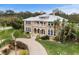 Elegant tan two-story home featuring a metal roof, arched windows, a front balcony, and a brick-paved driveway at 1665 Blue Heron Ln, Lakeland, FL 33813